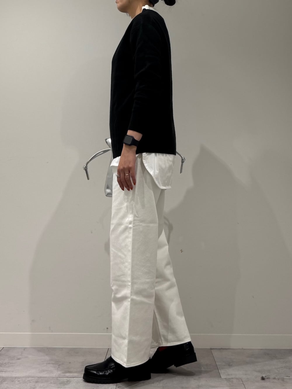 シルバー系のショルダーバッグ、ホワイト系のデニムパンツ、ブラック系のローファーを着用したレディースの冬コーディネートの5枚目の写真