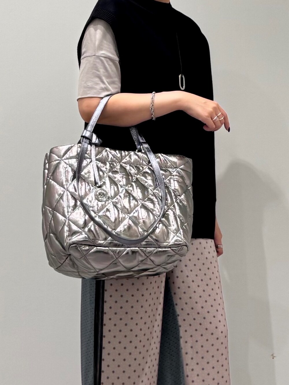 シルバー系のトートバッグ、ベージュ系のその他パンツ、ブラック系のベストを着用したレディースの秋コーディネートの6枚目の写真