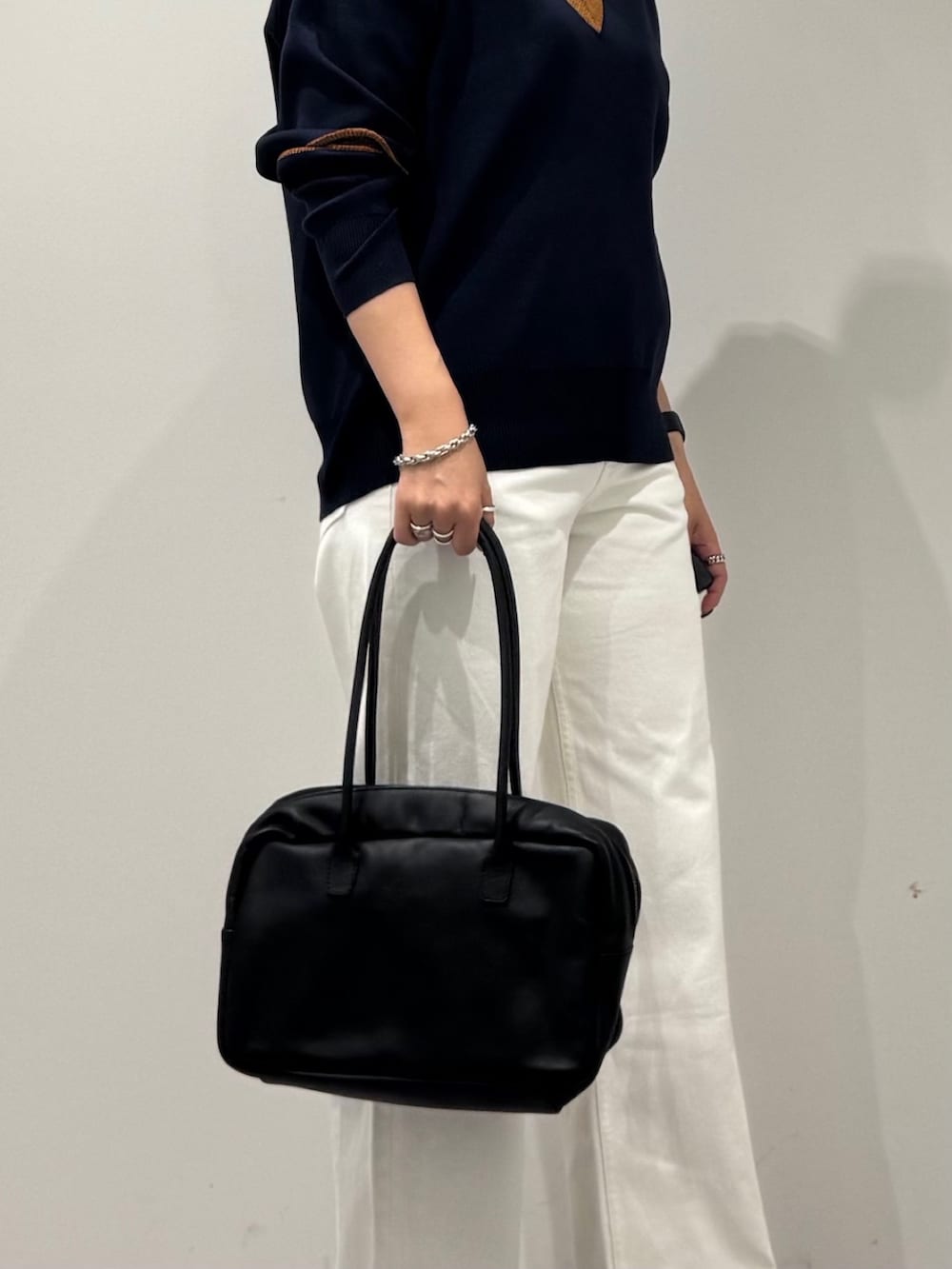 ブラック系のボストンバッグ、ホワイト系のデニムパンツ、ブラック系のローファーを着用したレディースの冬コーディネートの8枚目の写真