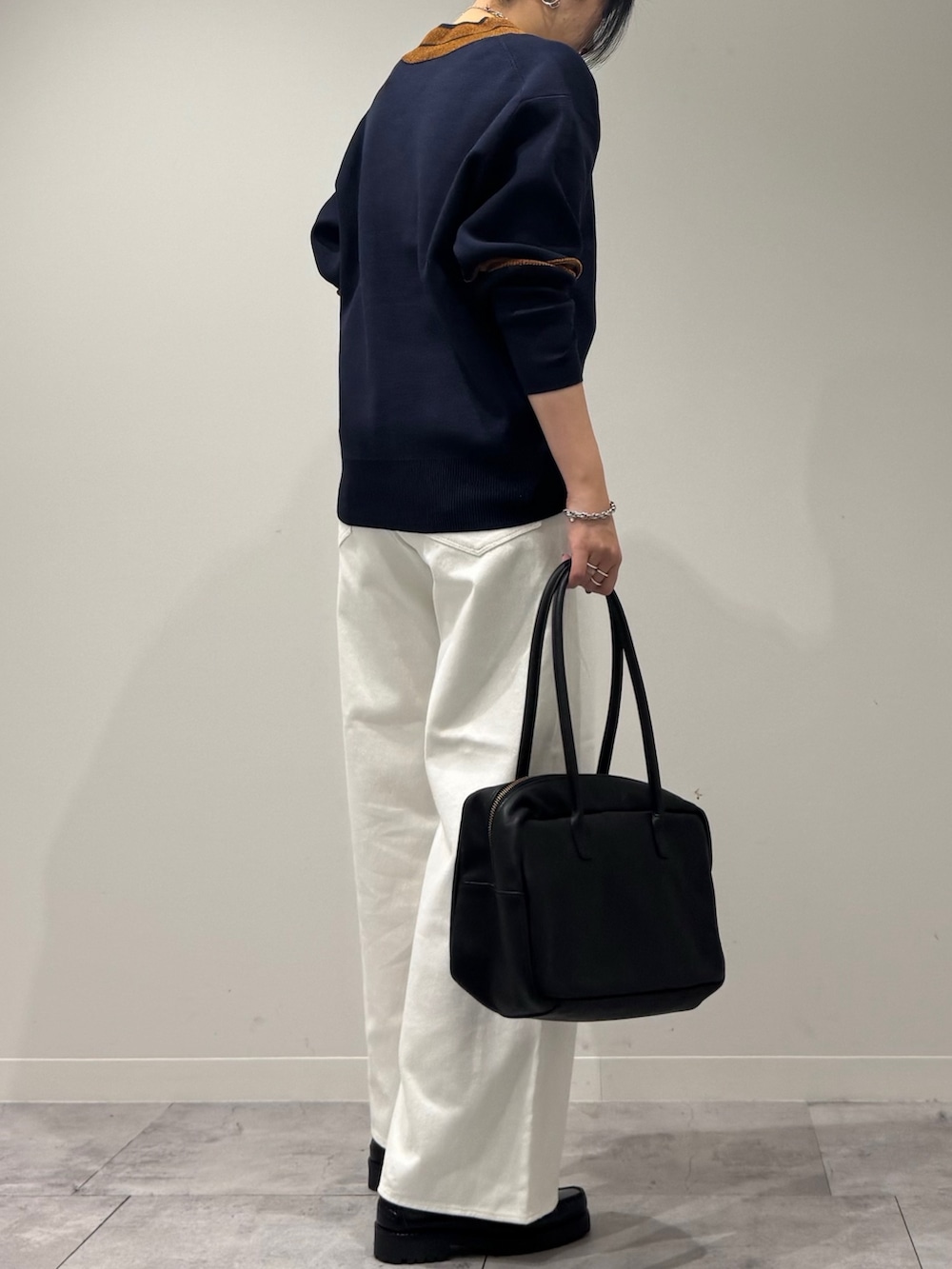 ブラック系のボストンバッグ、ホワイト系のデニムパンツ、ブラック系のローファーを着用したレディースの冬コーディネートの3枚目の写真