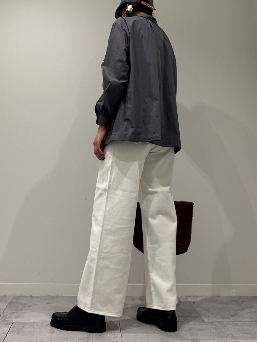 ブラウン系のトートバッグ、ホワイト系のデニムパンツ、ブラック系のローファーを着用したレディースの秋コーディネートの4枚目の写真