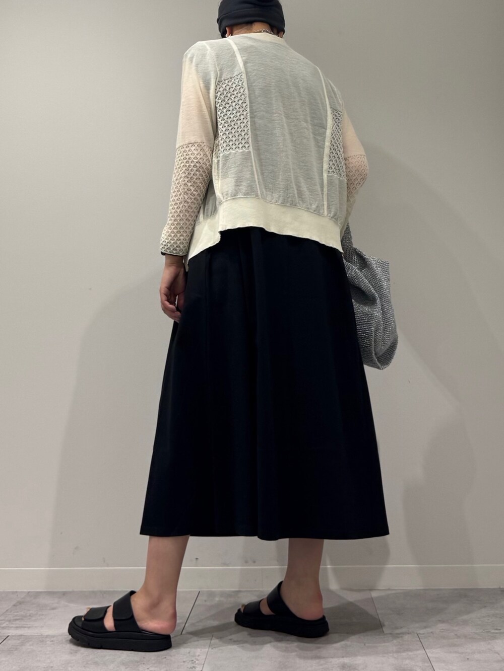 シルバー系のかごバッグ、ブラック系のワンピース、ホワイト系のカーディガン/ボレロを着用したレディースの秋コーディネートの5枚目の写真