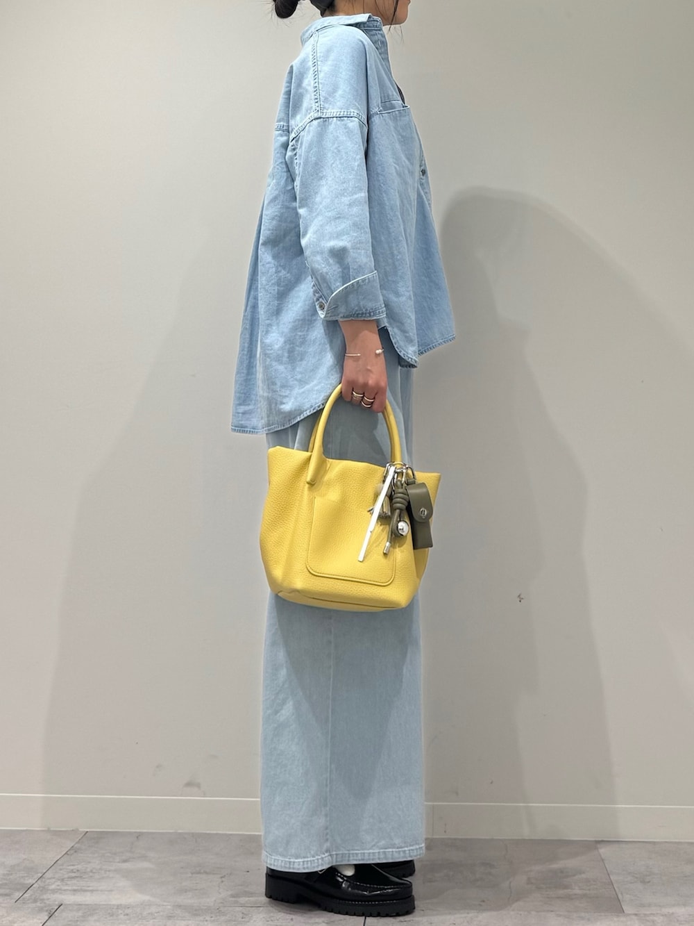 イエロー系のショルダーバッグ、ブルー系のデニムパンツ、ブラック系のローファーを着用したレディースの春コーディネートの6枚目の写真