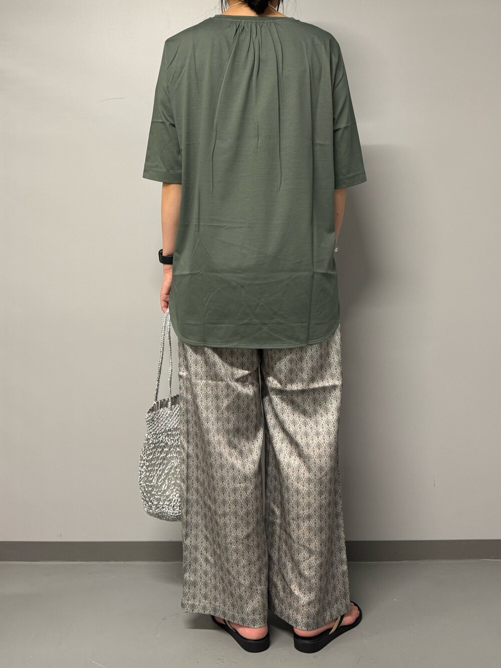 グリーン系のTシャツ/カットソー、ベージュ系のその他パンツ、シルバー系のかごバッグを着用したレディースの夏コーディネートの3枚目の写真