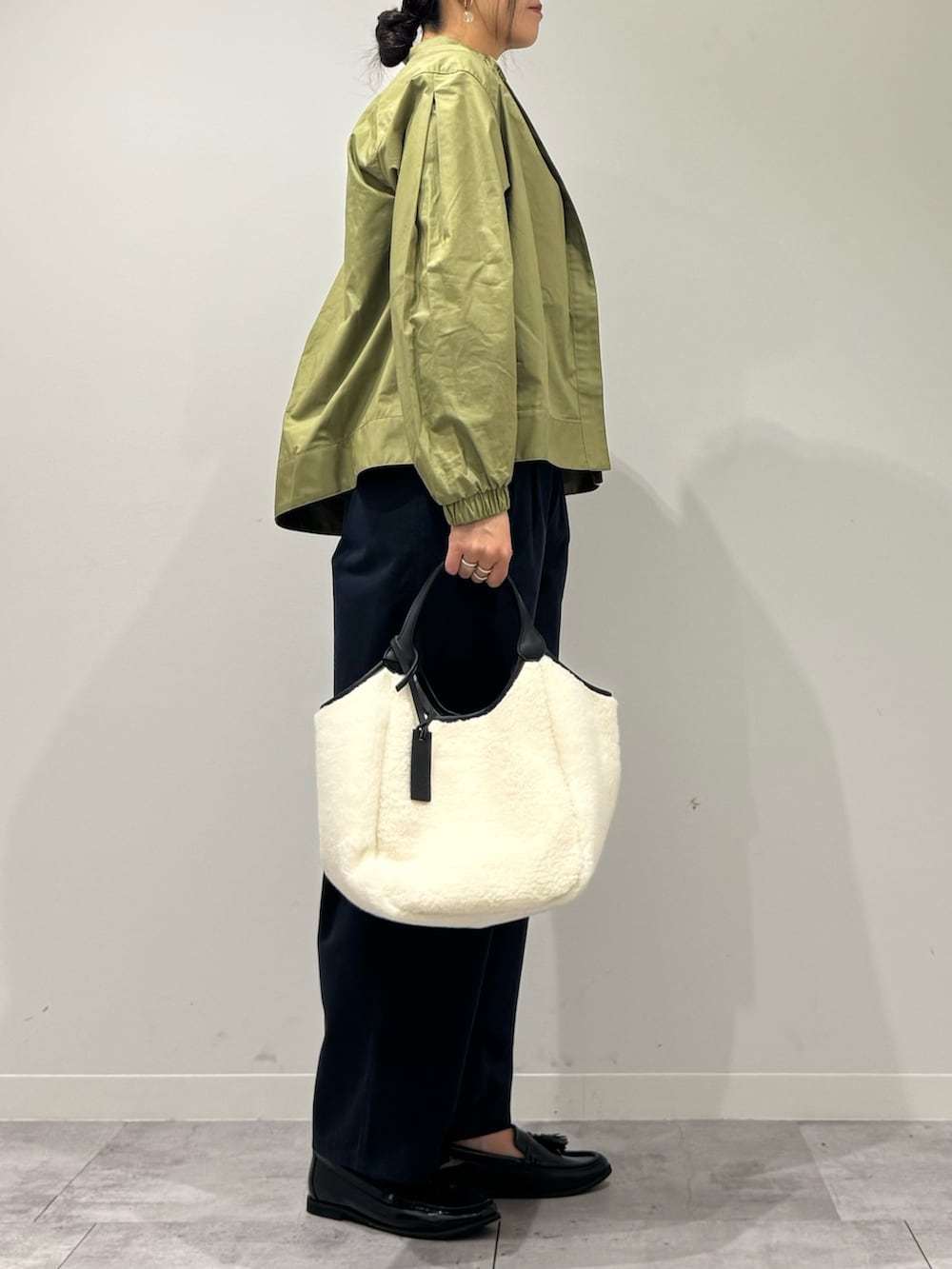 ホワイト系のトートバッグ、ブルー系のチノパンツ、グリーン系のブルゾンを着用したレディースの秋コーディネートの2枚目の写真