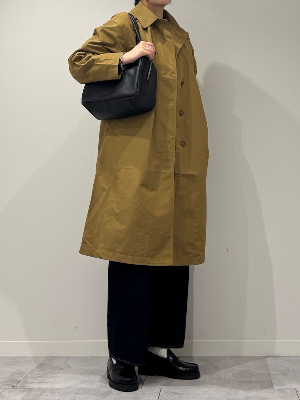 ブラック系のボストンバッグ、ベージュ系のダウンジャケット/コート、ブルー系のデニムパンツを着用したレディースの冬コーディネートの2枚目の写真