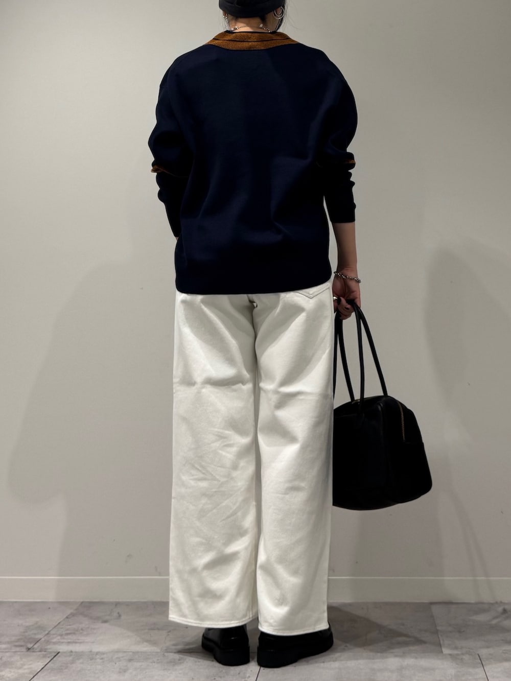 ブラック系のボストンバッグ、ホワイト系のデニムパンツ、ブラック系のローファーを着用したレディースの冬コーディネートの4枚目の写真