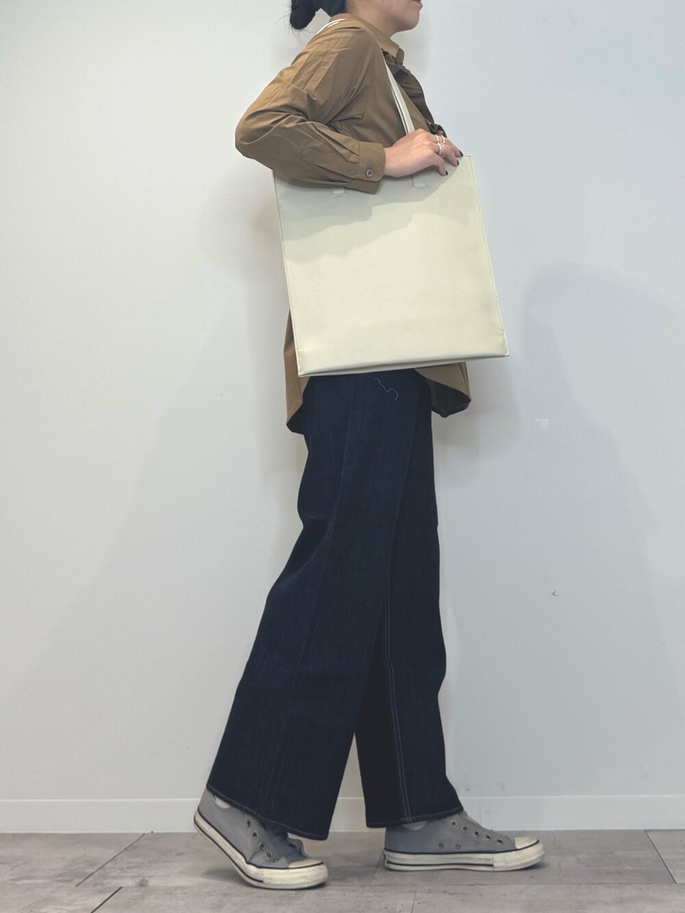 ホワイト系のトートバッグ、ブルー系のデニムパンツ、ブラウン系のシャツ/ブラウスを着用したレディースの春コーディネートの2枚目の写真