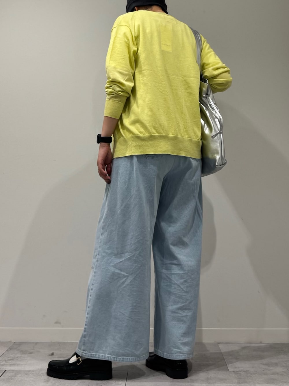 シルバー系のトートバッグ、ブラック系のローファー、ブルー系のデニムパンツを着用したレディースの春コーディネートの4枚目の写真