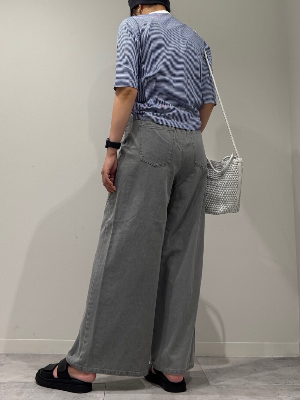 ホワイト系のトートバッグ、グレー系のデニムパンツ、ブラック系のサンダルを着用したレディースの夏コーディネートの3枚目の写真