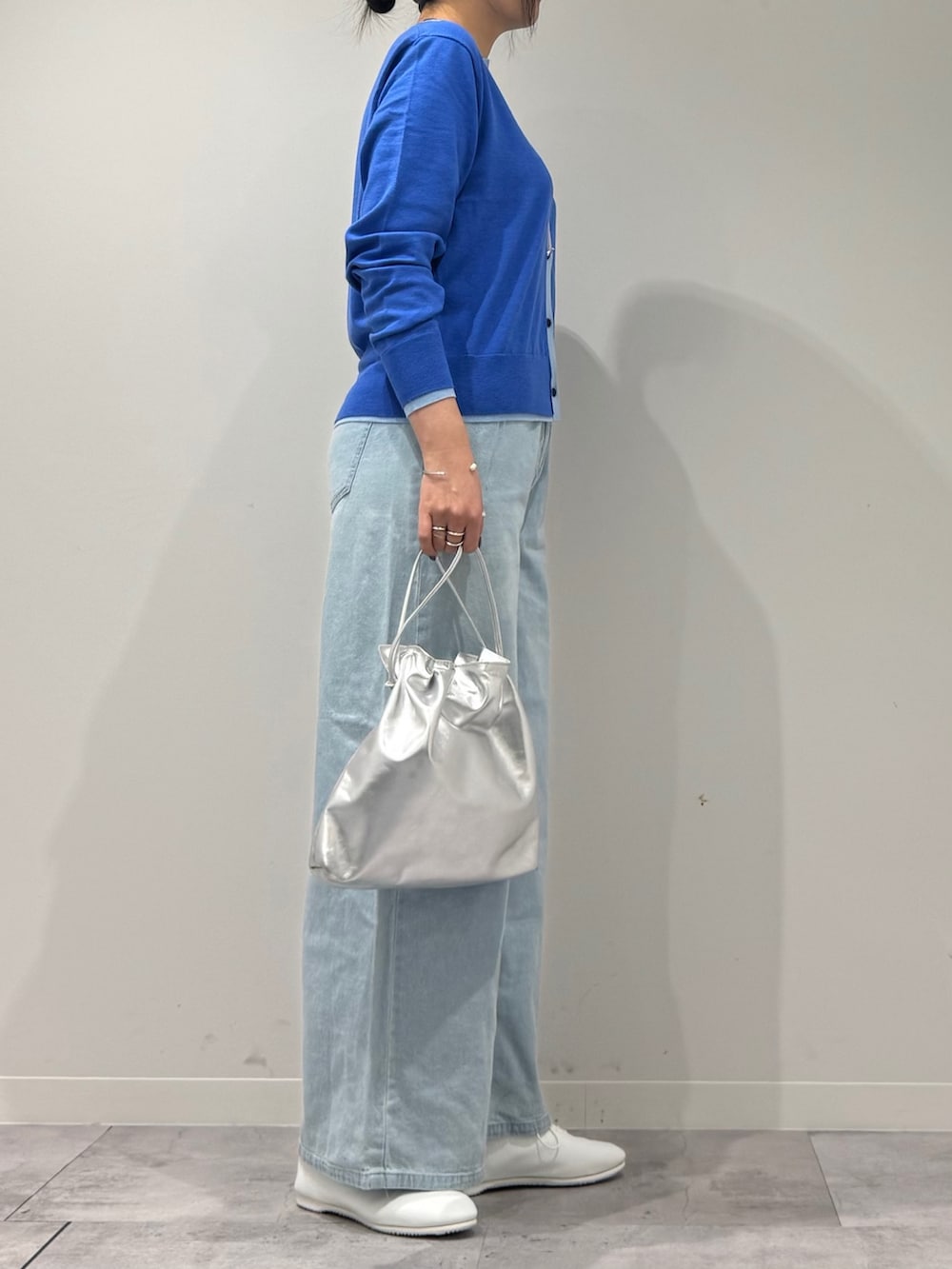 シルバー系のショルダーバッグ、ブルー系のカーディガン/ボレロ、ブルー系のデニムパンツを着用したレディースの冬コーディネートの2枚目の写真