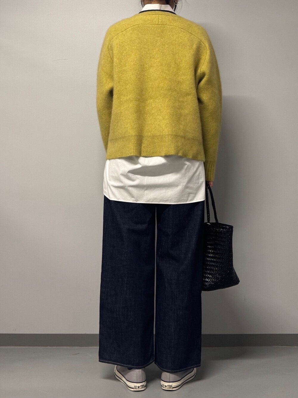 イエロー系のニット/セーター、ホワイト系のシャツ/ブラウス、ブルー系のデニムパンツを着用したレディースの冬コーディネートの2枚目の写真