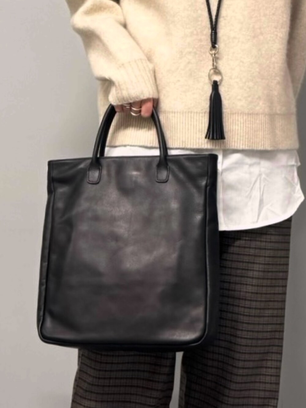 ベージュ系のニット/セーター、ブラウン系のその他パンツ、ブラック系のトートバッグを着用したレディースの冬コーディネートの7枚目の写真