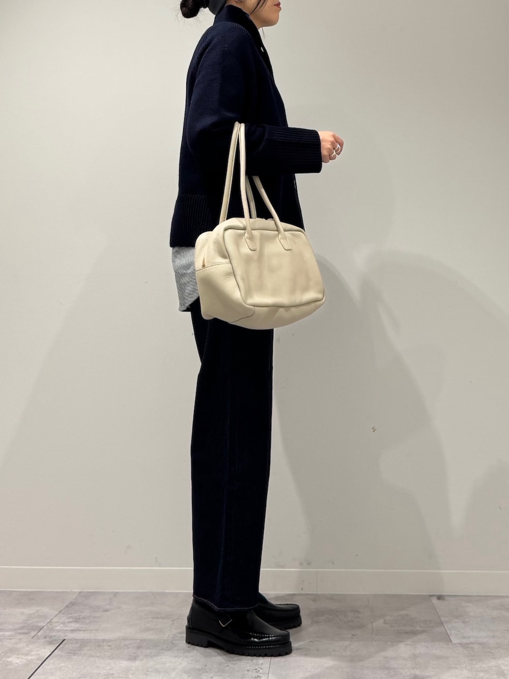 ベージュ系のボストンバッグ、ブルー系のデニムパンツ、ブラック系のローファーを着用したレディースの冬コーディネートの2枚目の写真