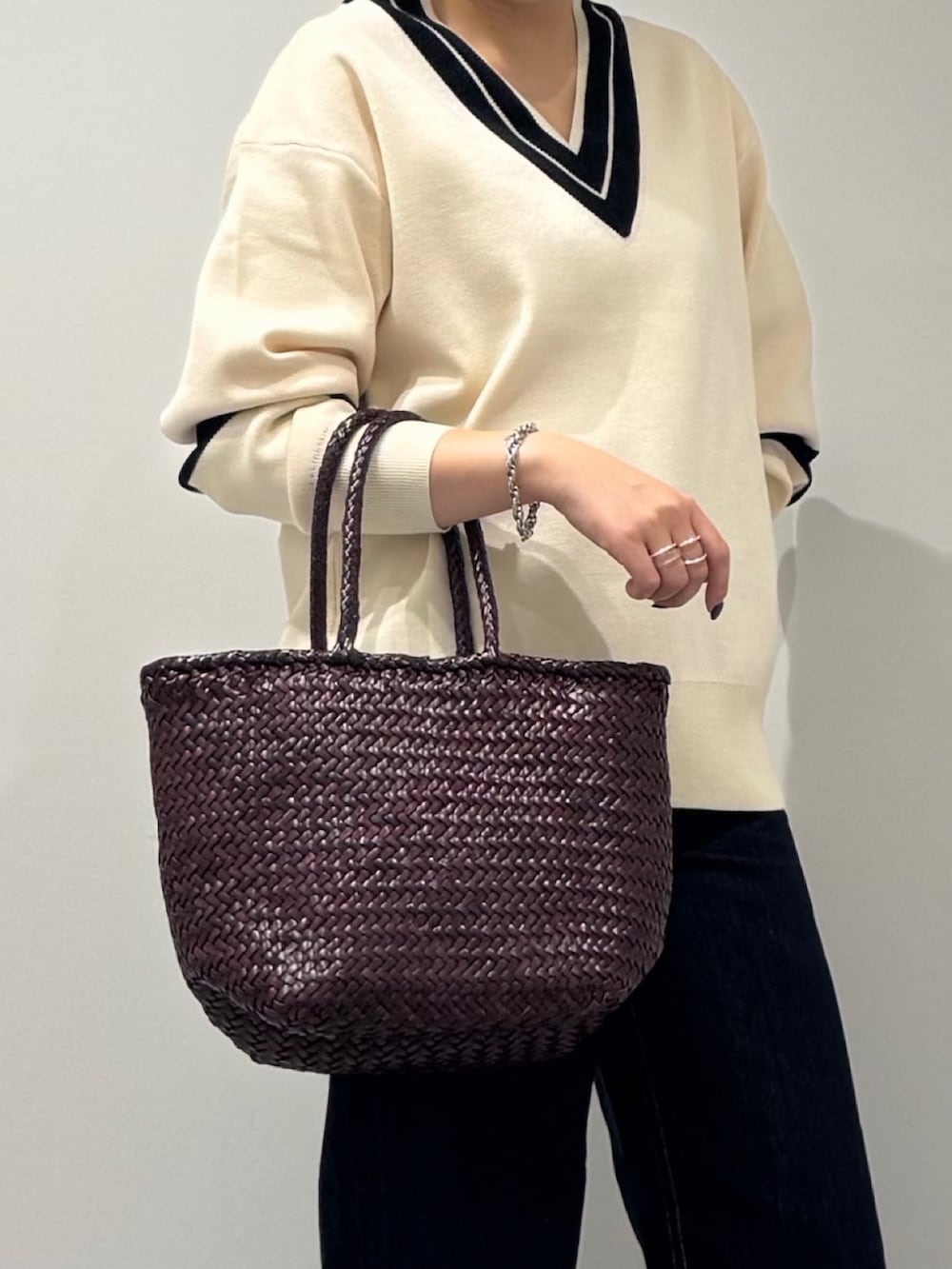 パープル系のトートバッグ、ブルー系のデニムパンツ、ブラック系のローファーを着用したレディースの冬コーディネートの8枚目の写真