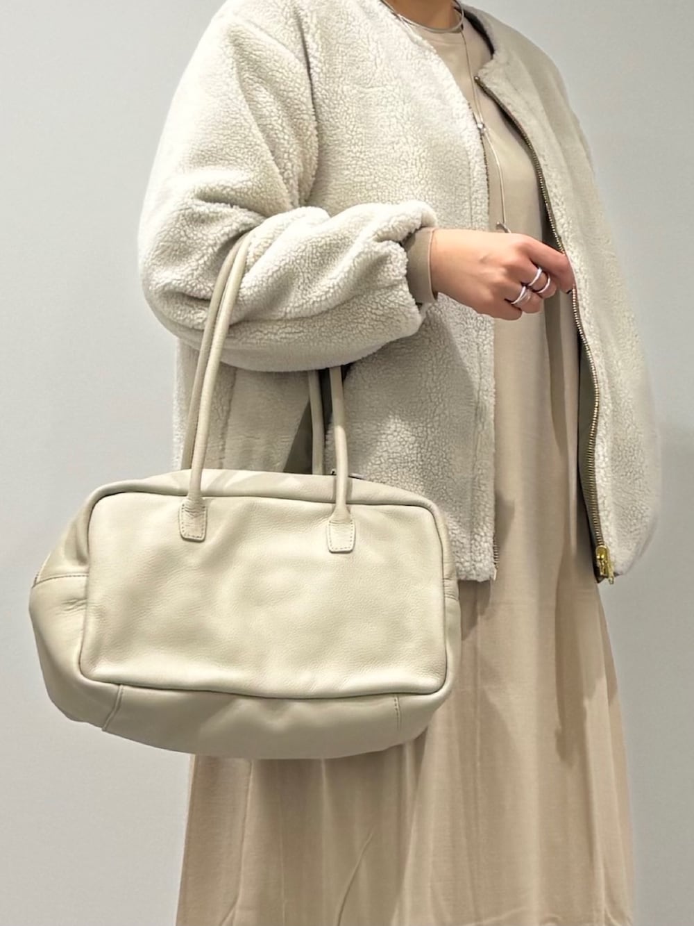 ベージュ系のボストンバッグ、ベージュ系のワンピース、ブルー系のデニムパンツを着用したレディースの春コーディネートの8枚目の写真