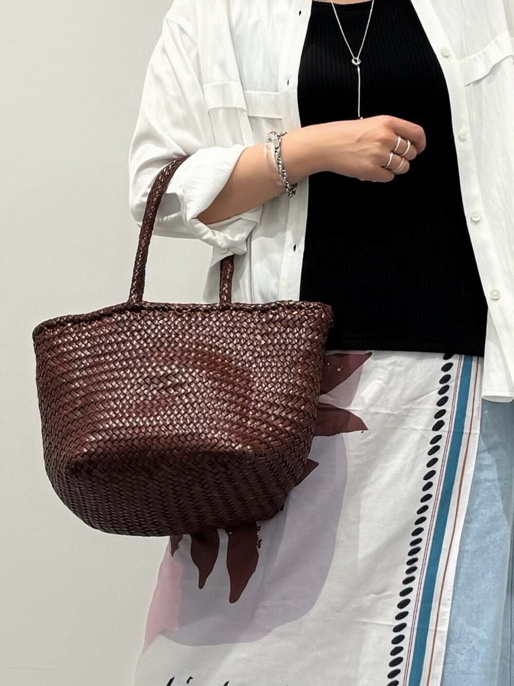 ブラウン系のトートバッグ、ブルー系のデニムパンツ、ブラック系のサンダルを着用したレディースの秋コーディネートの7枚目の写真