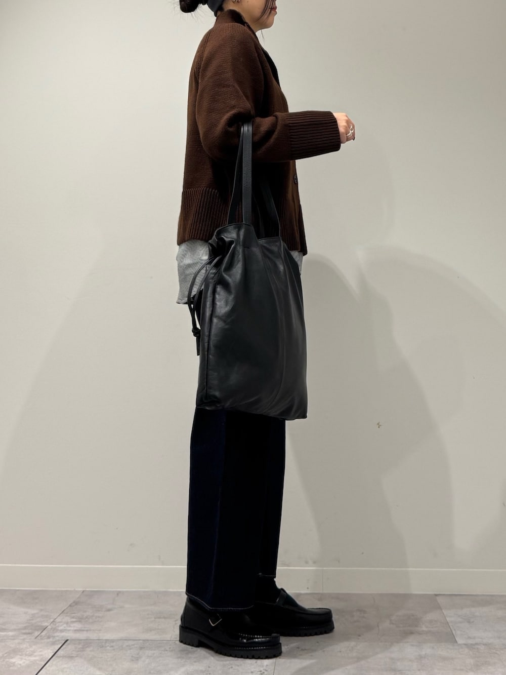 ブラック系のトートバッグ、ブルー系のデニムパンツ、ブラック系のローファーを着用したレディースの冬コーディネートの2枚目の写真