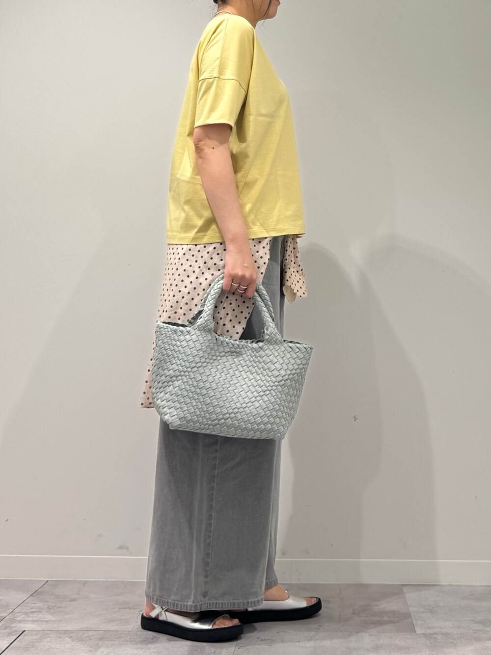 グレー系のトートバッグ、グレー系のデニムパンツ、ホワイト系のシャツ/ブラウスを着用したレディースの春コーディネートの2枚目の写真