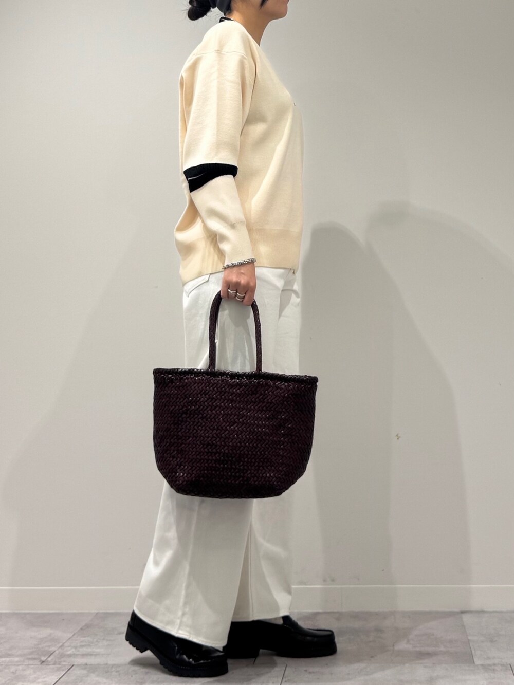 パープル系のトートバッグ、ホワイト系のデニムパンツ、ブラック系のローファーを着用したレディースの冬コーディネートの2枚目の写真