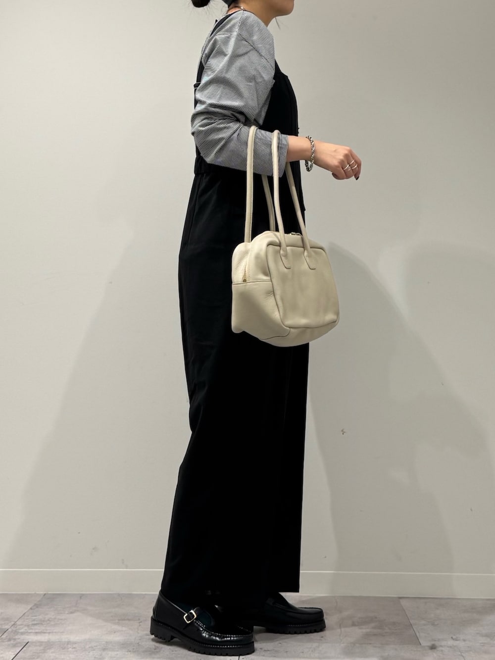 ベージュ系のボストンバッグ、ブラック系のサロペット/オーバーオール、ブラック系のローファーを着用したレディースの春コーディネートの2枚目の写真