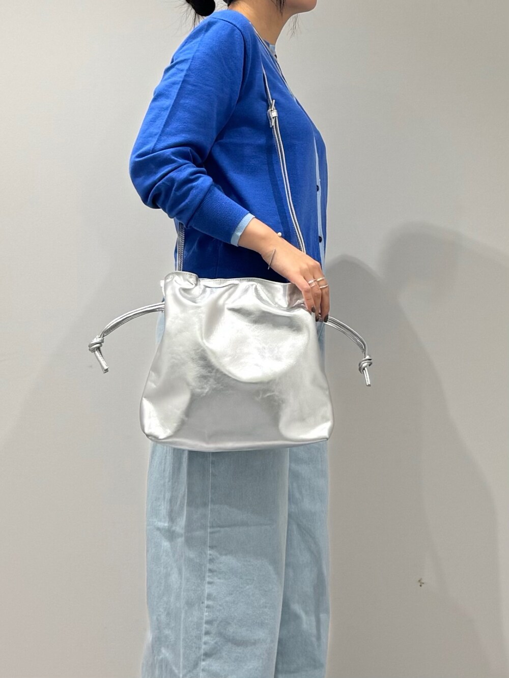 シルバー系のショルダーバッグ、ブルー系のカーディガン/ボレロ、ブルー系のデニムパンツを着用したレディースの冬コーディネートの7枚目の写真