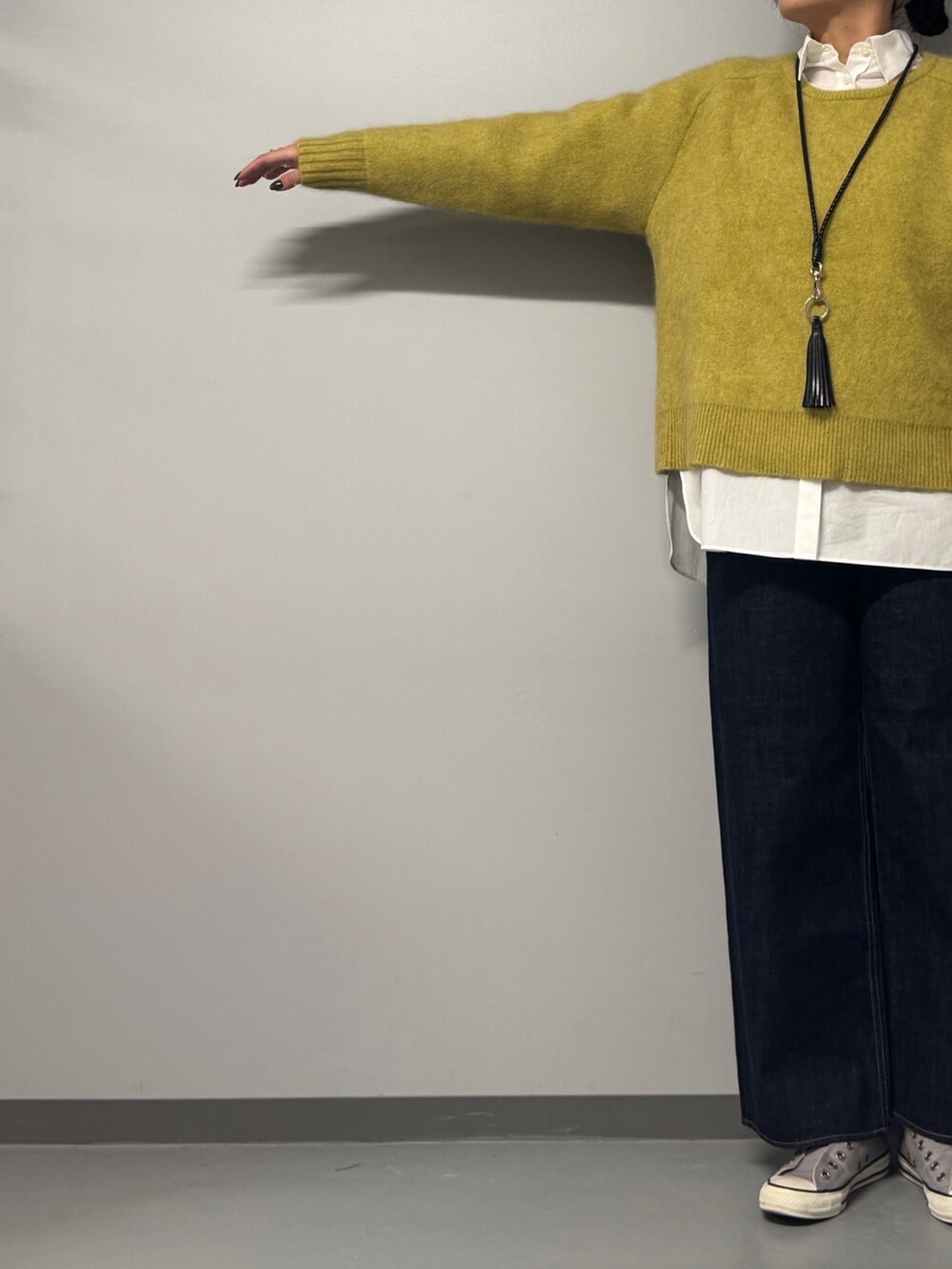 イエロー系のニット/セーター、ホワイト系のシャツ/ブラウス、ブルー系のデニムパンツを着用したレディースの冬コーディネートの7枚目の写真