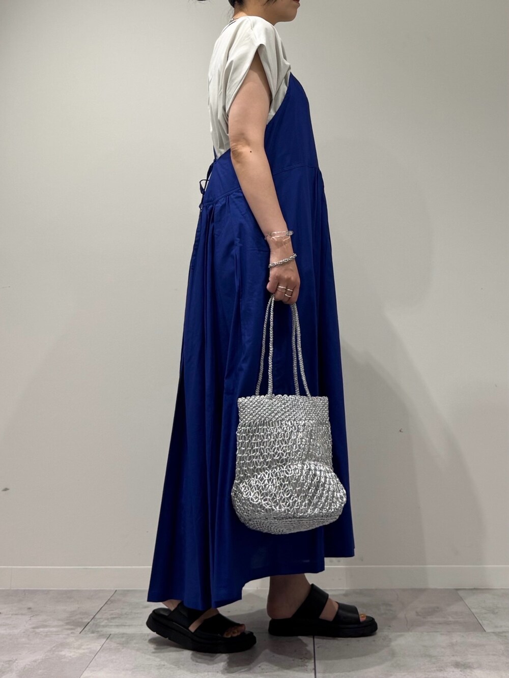 ブルー系のワンピース、シルバー系のかごバッグ、ブラック系のサンダルを着用したレディースの夏コーディネートの2枚目の写真