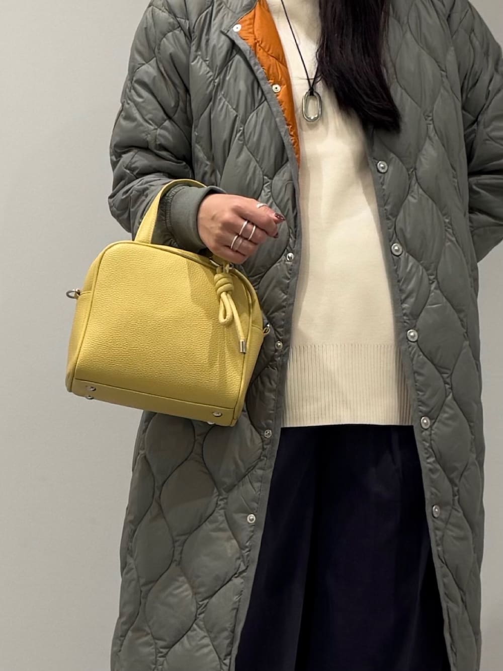 イエロー系のボストンバッグ、ブラック系のローファー、ホワイト系のベストを着用したレディースの秋コーディネートの9枚目の写真