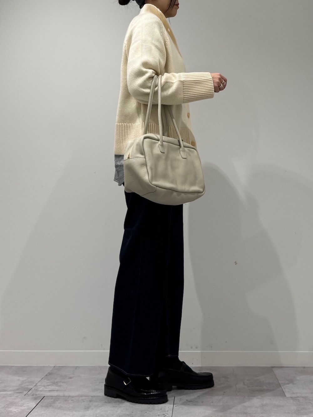 ベージュ系のボストンバッグ、ブルー系のデニムパンツ、ブラック系のローファーを着用したレディースの冬コーディネートの2枚目の写真