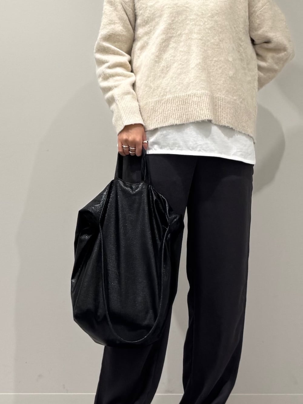 ブラック系のトートバッグ、ホワイト系のニット/セーター、ホワイト系のTシャツ/カットソーを着用したレディースの冬コーディネートの7枚目の写真