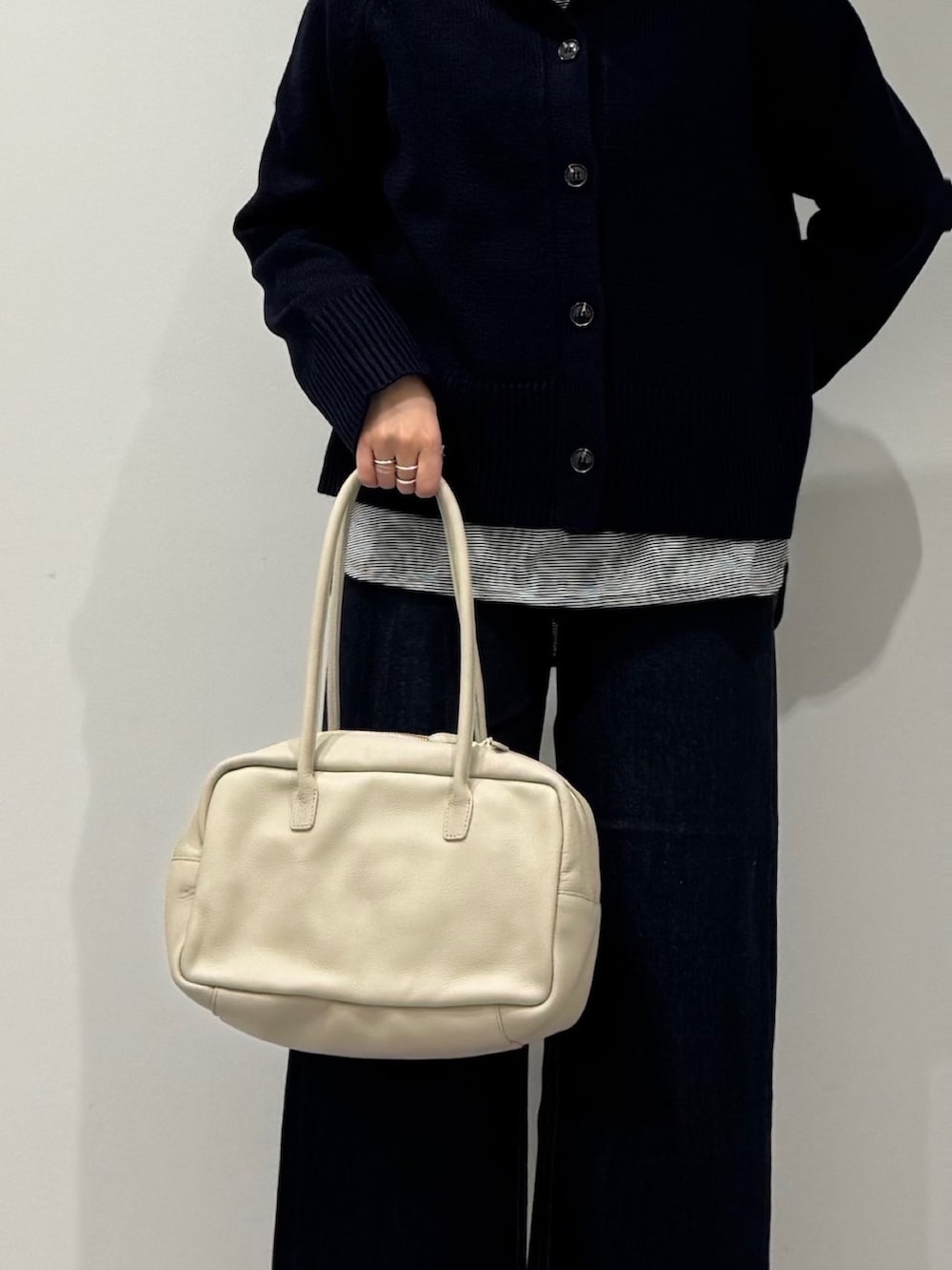 ベージュ系のボストンバッグ、ブルー系のデニムパンツ、ブラック系のローファーを着用したレディースの冬コーディネートの6枚目の写真