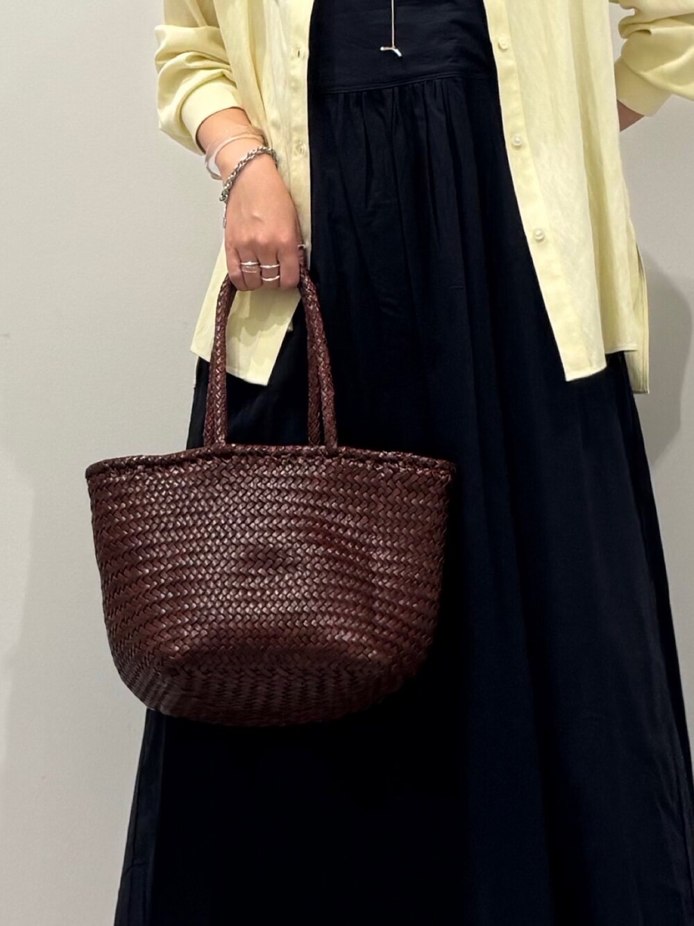 ブラウン系のトートバッグ、ブラック系のワンピース、イエロー系のシャツ/ブラウスを着用したレディースの秋コーディネートの7枚目の写真