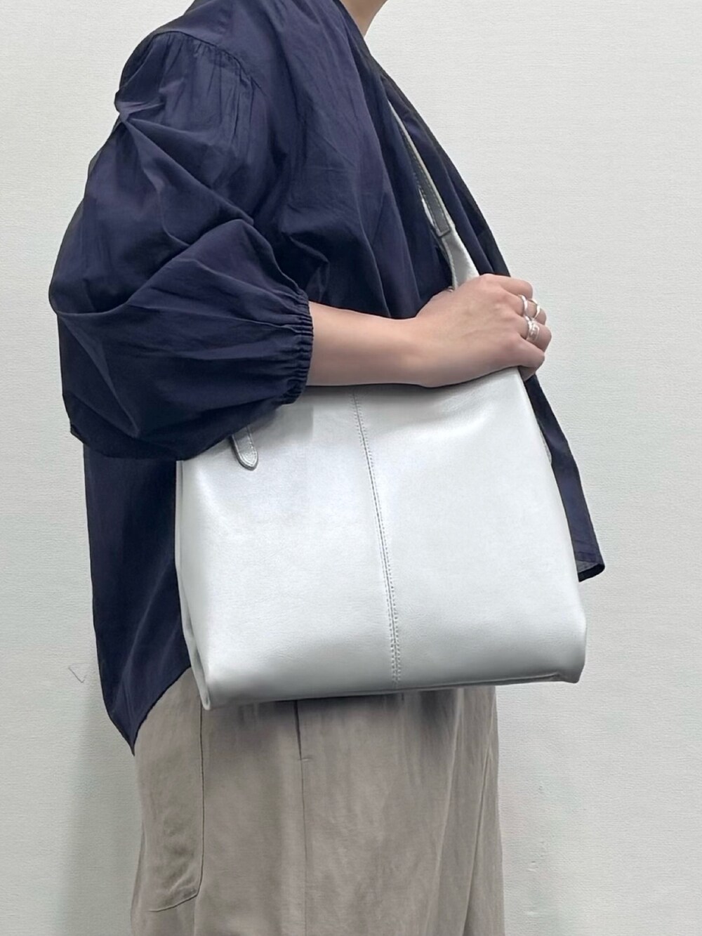 シルバー系のトートバッグ、ベージュ系のサロペット/オーバーオール、ホワイト系のTシャツ/カットソーを着用したレディースの春コーディネートの8枚目の写真