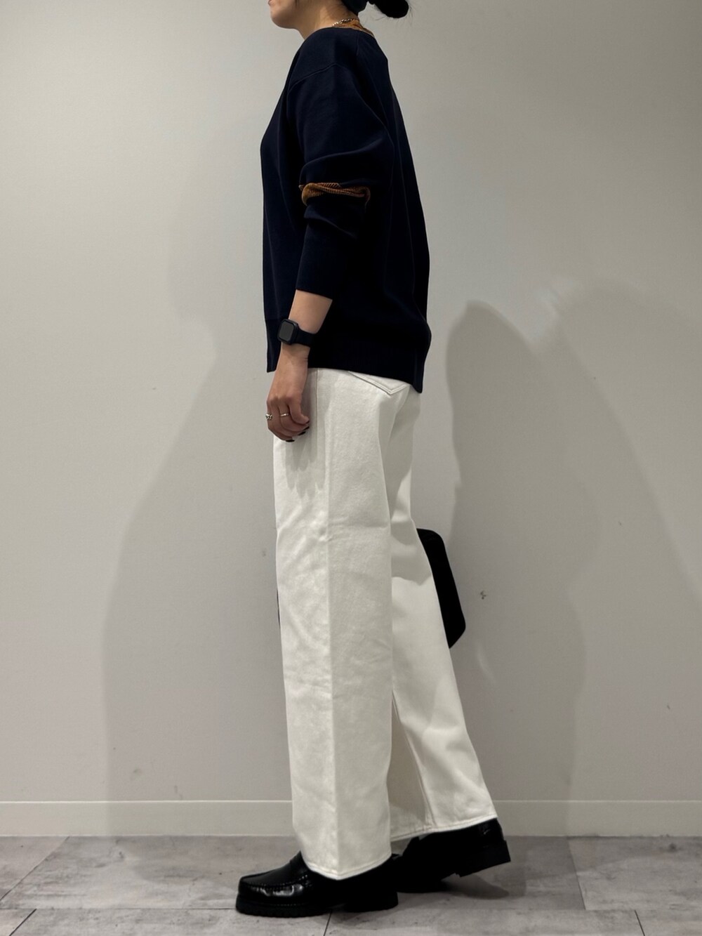 ブラック系のボストンバッグ、ホワイト系のデニムパンツ、ブラック系のローファーを着用したレディースの冬コーディネートの5枚目の写真