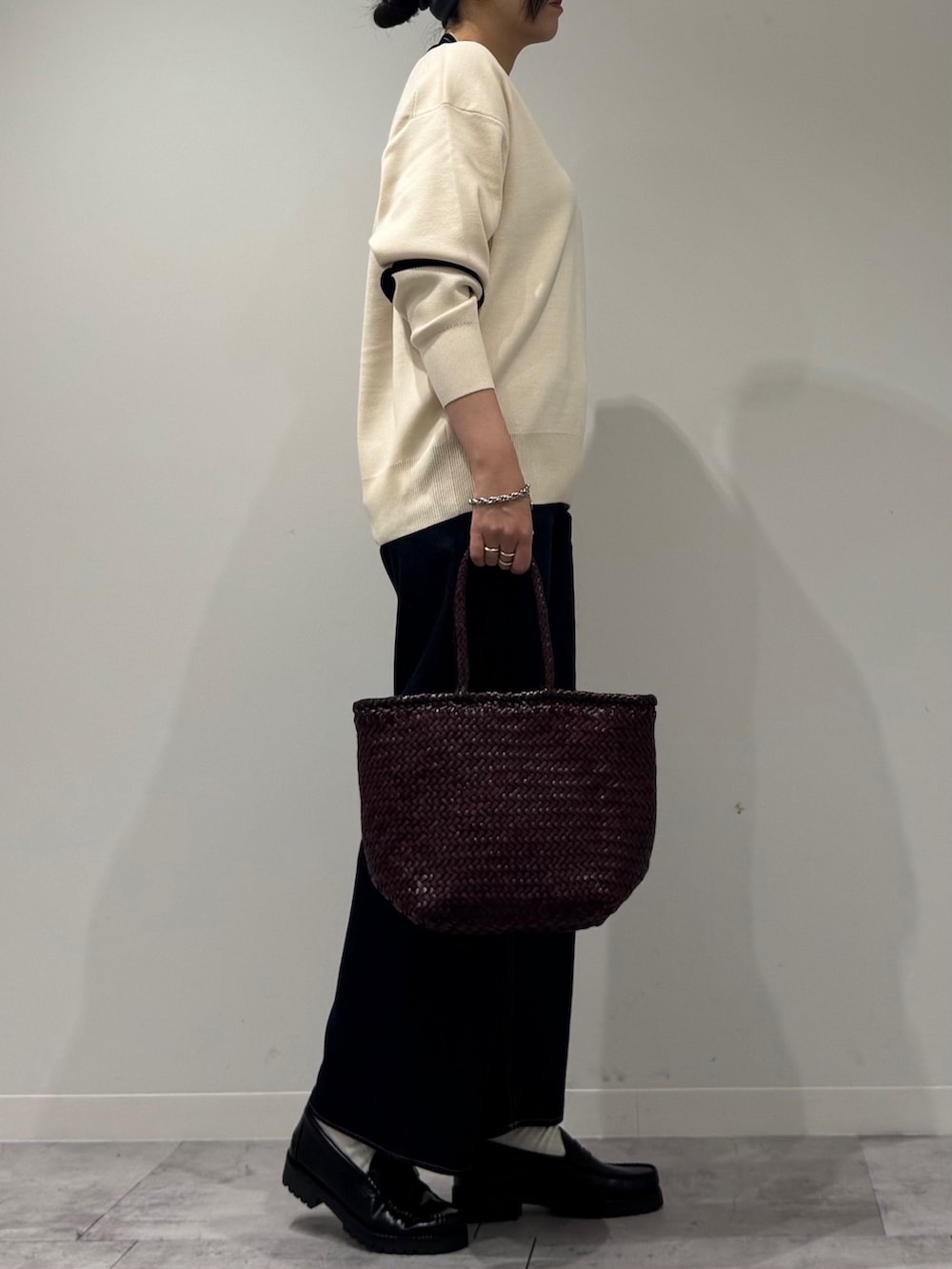 パープル系のトートバッグ、ブルー系のデニムパンツ、ブラック系のローファーを着用したレディースの冬コーディネートの2枚目の写真