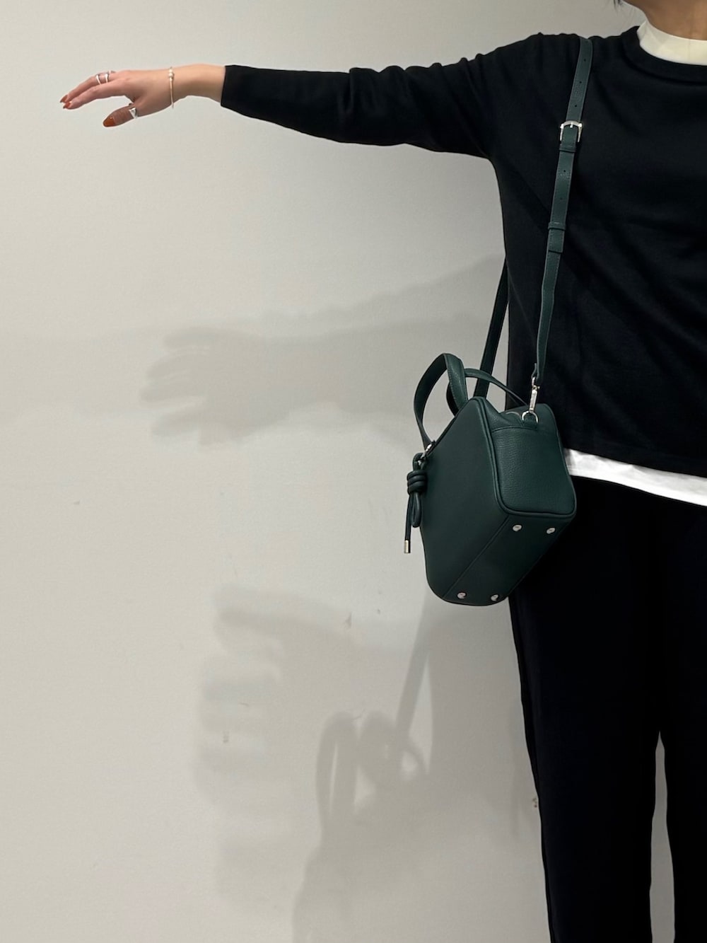 グリーン系のボストンバッグ、ブラック系のニット/セーター、ホワイト系のTシャツ/カットソーを着用したレディースの冬コーディネートの5枚目の写真