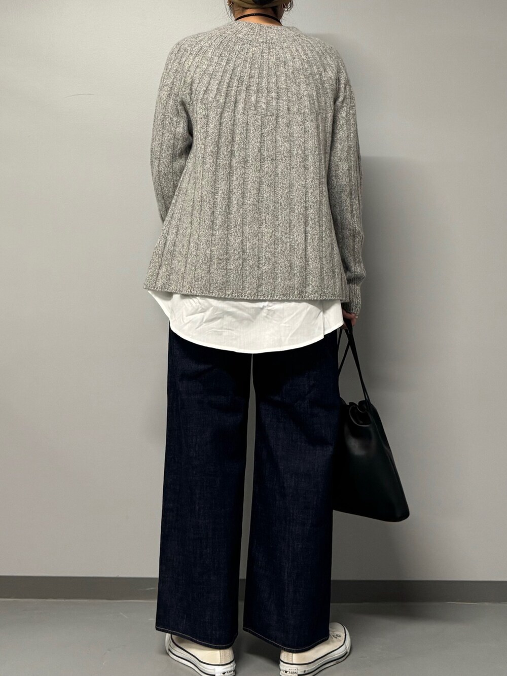 ブルー系のデニムパンツ、ブラック系のショルダーバッグ、グレー系のニット/セーターを着用したレディースの秋コーディネートの2枚目の写真