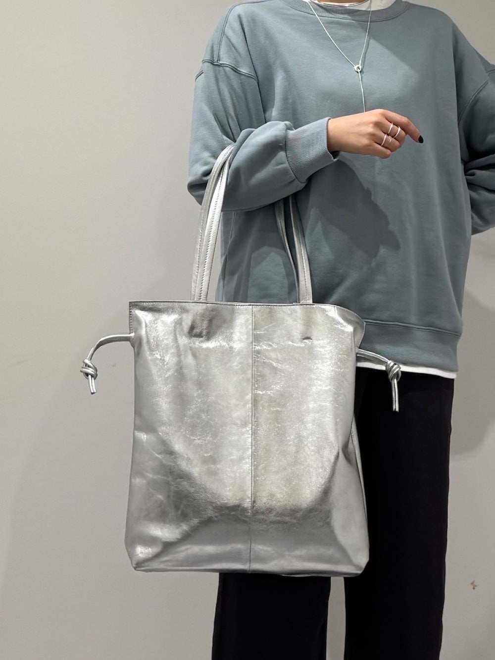 シルバー系のトートバッグ、ブルー系のスウェット、ホワイト系のTシャツ/カットソーを着用したレディースの冬コーディネートの7枚目の写真