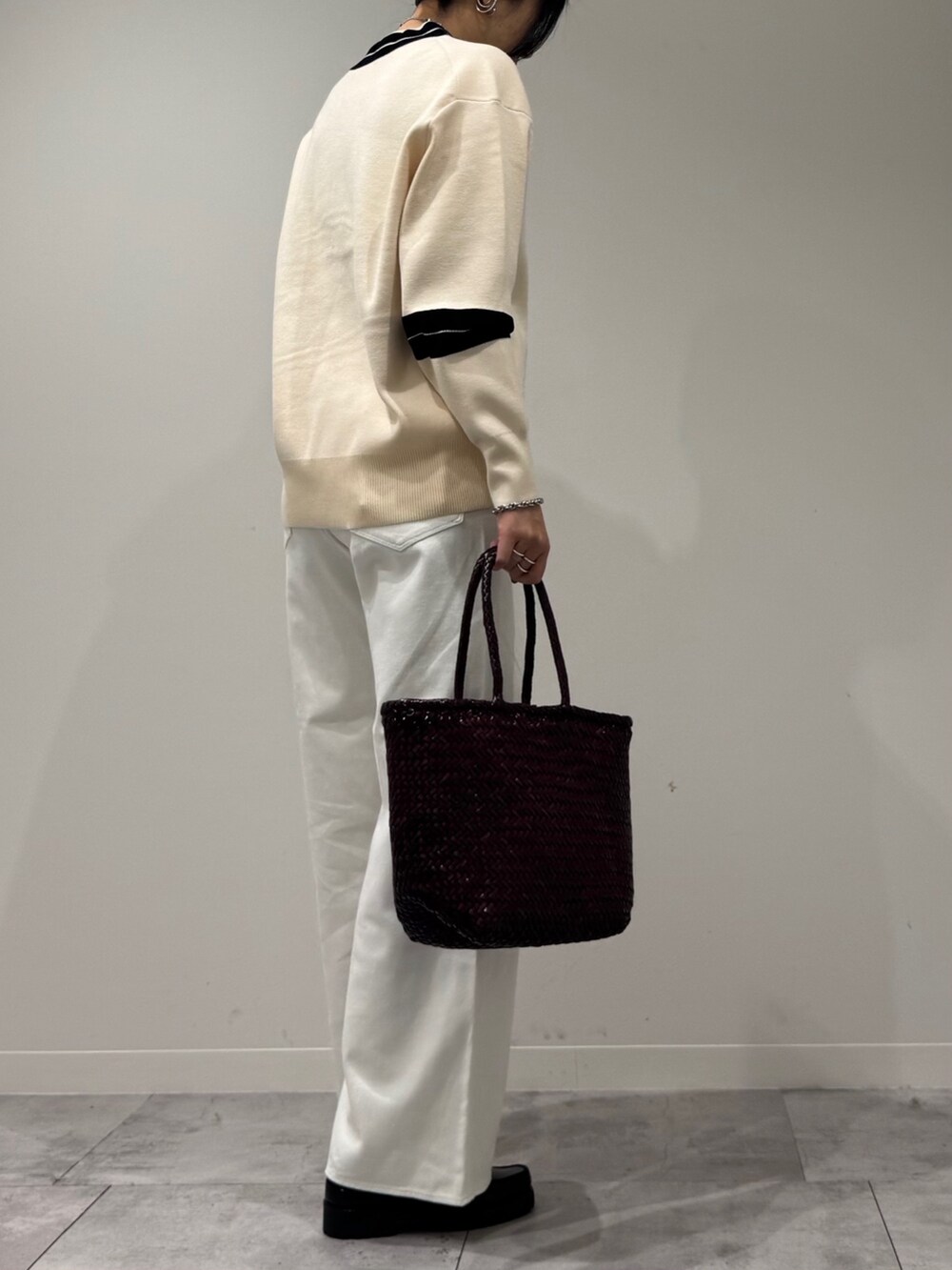 パープル系のトートバッグ、ホワイト系のデニムパンツ、ブラック系のローファーを着用したレディースの冬コーディネートの3枚目の写真