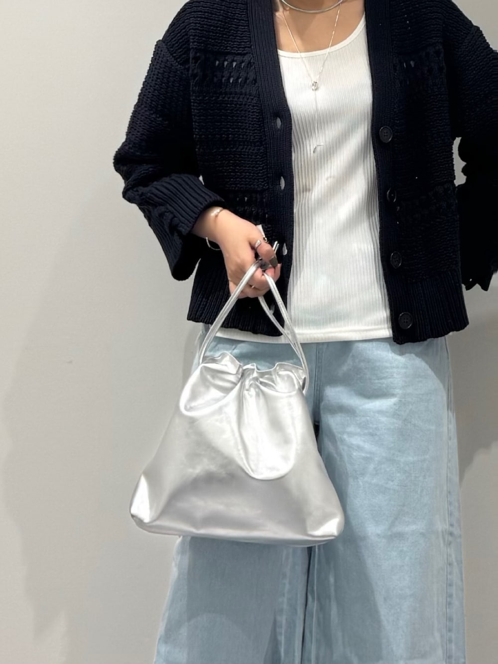 シルバー系のショルダーバッグ、ブルー系のデニムパンツ、ホワイト系のタンクトップを着用したレディースの春コーディネートの7枚目の写真