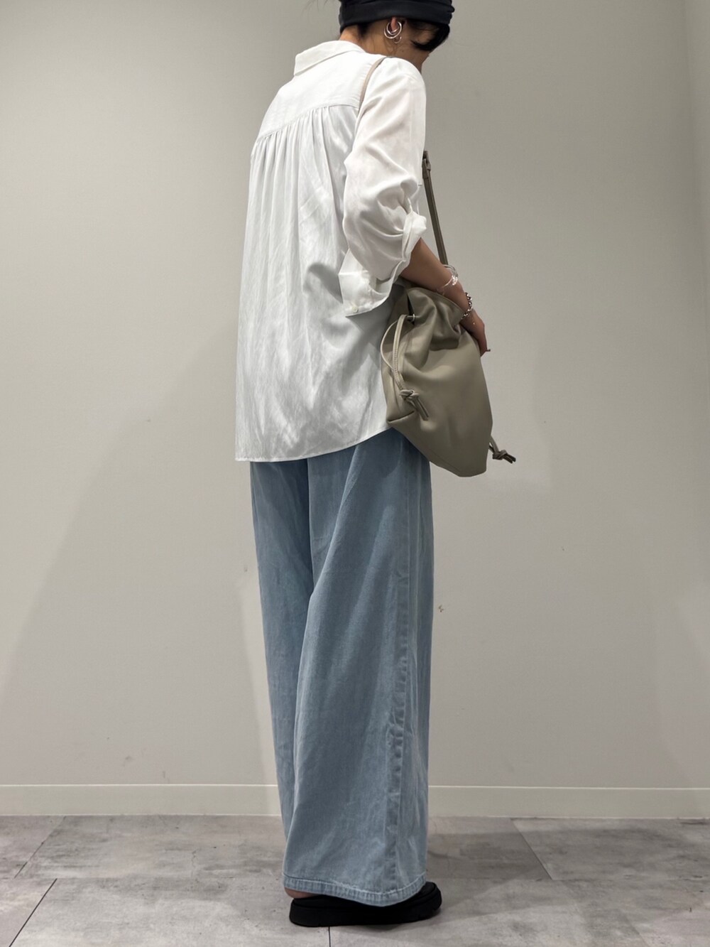 ベージュ系のショルダーバッグ、ブルー系のデニムパンツ、ブラック系のサンダルを着用したレディースの秋コーディネートの3枚目の写真