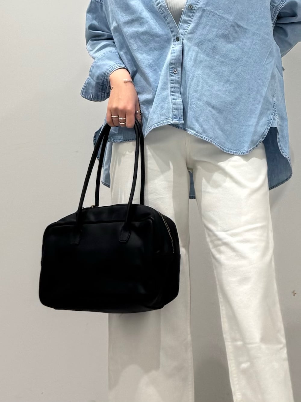 ブラック系のボストンバッグ、ホワイト系のデニムパンツ、ブルー系のシャツ/ブラウスを着用したレディースの春コーディネートの7枚目の写真