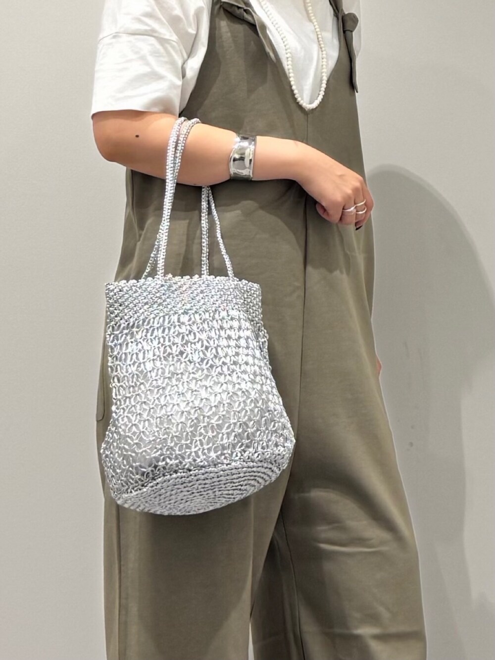 シルバー系のかごバッグ、ブラック系のサンダル、ホワイト系のTシャツ/カットソーを着用したレディースの夏コーディネートの7枚目の写真