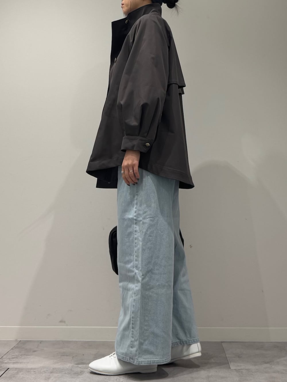 グレー系のトレンチコート、ブラック系のボストンバッグ、ブルー系のデニムパンツを着用したレディースの冬コーディネートの5枚目の写真