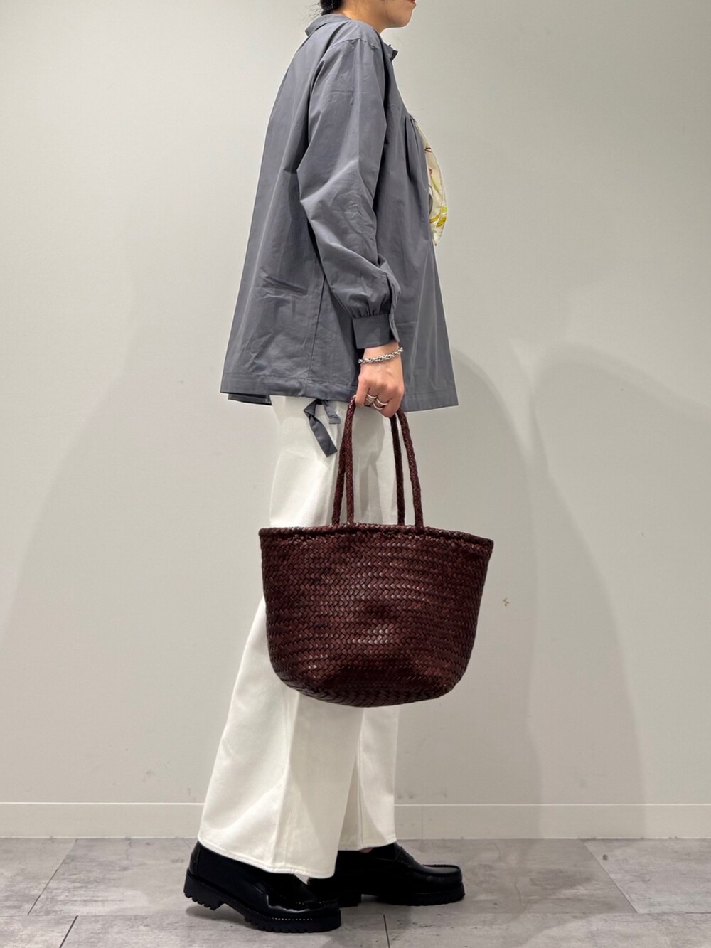 ブラウン系のトートバッグ、ホワイト系のデニムパンツ、ブラック系のローファーを着用したレディースの秋コーディネートの2枚目の写真