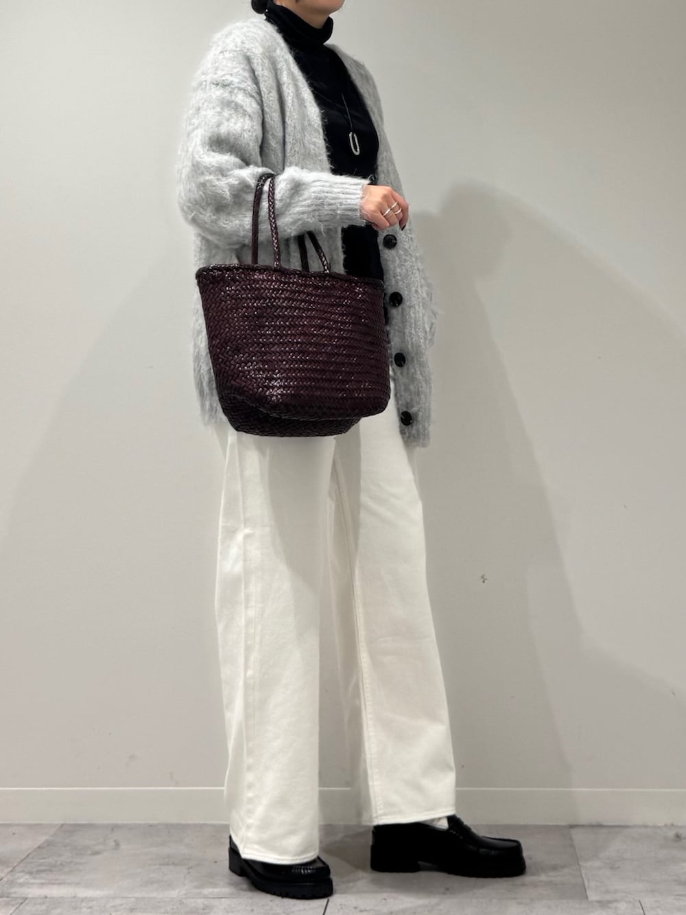 パープル系のトートバッグ、ホワイト系のデニムパンツ、ブラック系のローファーを着用したレディースの冬コーディネートの2枚目の写真