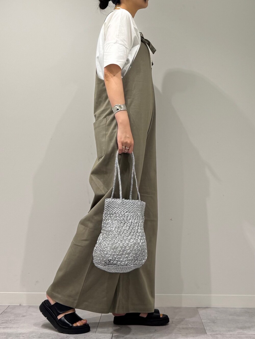 シルバー系のかごバッグ、ブラック系のサンダル、ホワイト系のTシャツ/カットソーを着用したレディースの夏コーディネートの2枚目の写真