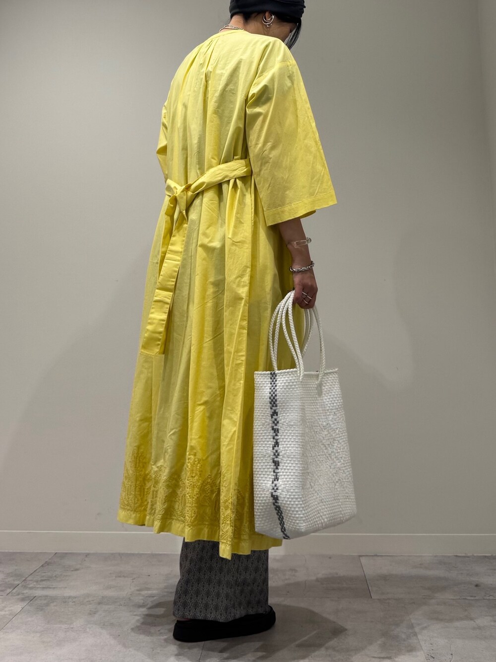 ホワイト系のかごバッグ、イエロー系のワンピース、ベージュ系のその他パンツを着用したレディースの夏コーディネートの4枚目の写真