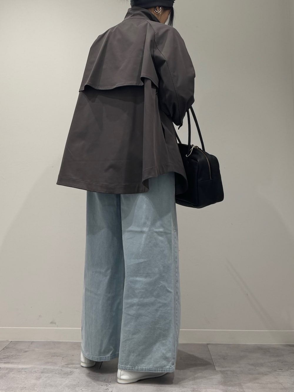 グレー系のトレンチコート、ブラック系のボストンバッグ、ブルー系のデニムパンツを着用したレディースの冬コーディネートの3枚目の写真